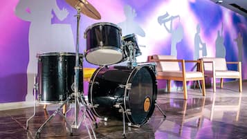Un set de percusión en una habitación con piso reflectante y un mural de músicos en la pared.
