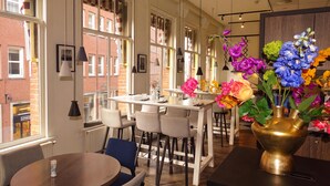 Un intérieur moderne avec de grandes fenêtres, un coin repas et un vase décoratif rempli de fleurs.