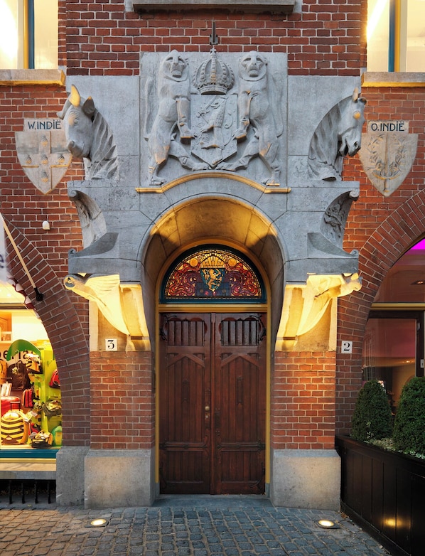 A building entrance with a double wooden door, a stained glass window, and a coat of arms above. - Berlage Hotel, BW Signature Collection (The Hague)