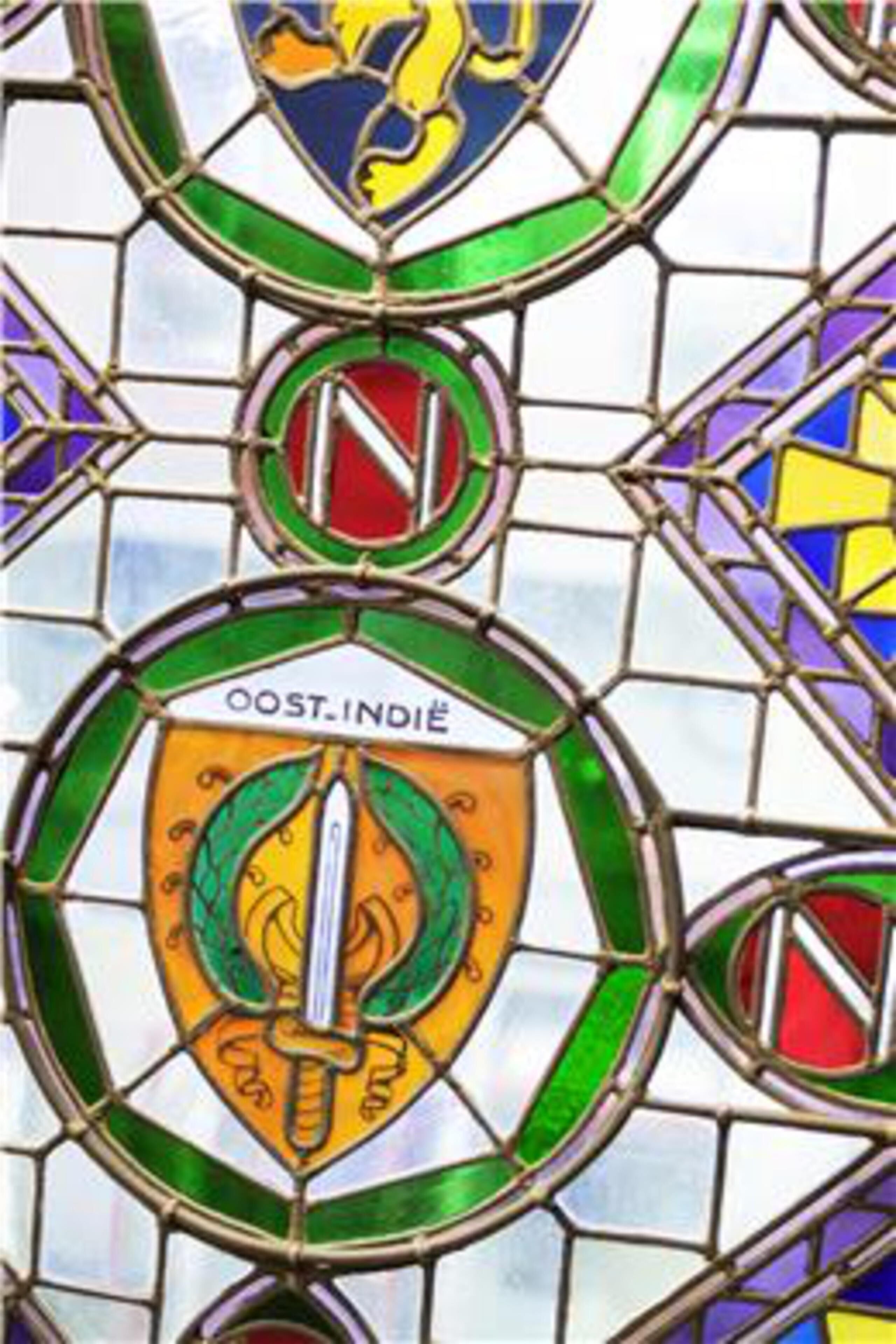 Een glas-in-loodraam met een schild en zwaard embleem.