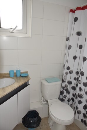 Ein Badezimmer mit Toilette, einem Waschbecken mit Marmorplatte und einer Blumendekor-Duschvorhang.