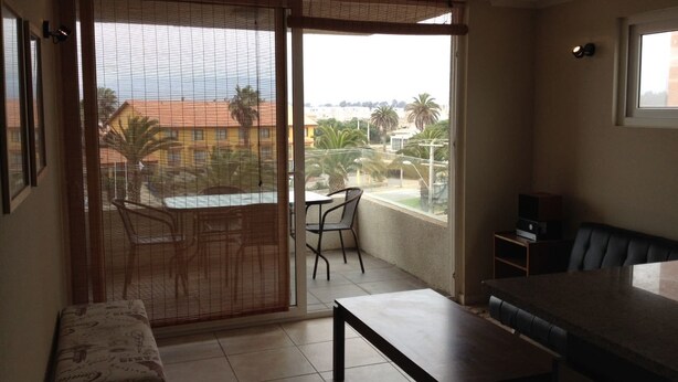 Een balkon met een tafel en stoelen, een bank en een televisie.