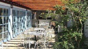 En uteplats med metallbord och -stolar, en pergola av trä och utsikt över ett berg.