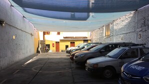 Uma área de estacionamento com vários carros estacionados sob um toldo azul.