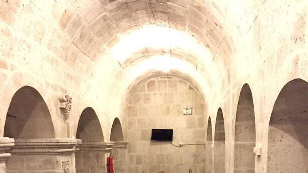 Uma sala de jantar com mesas e cadeiras, paredes de pedra e piso de azulejos.