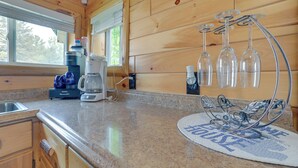 A kitchen with wooden walls, a granite countertop, a coffee maker, and a wine rack. - Cozy Houghton Lake Vacation Rental w/ Fireplace! (Houghton Lake)