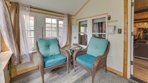 A cozy room with wicker chairs, a small table, and a view of the outside. - Cozy Houghton Lake Vacation Rental w/ Fireplace! (Houghton Lake)