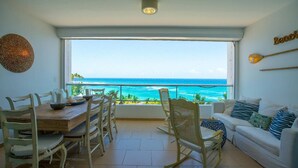 A dining area with a view of the ocean, a white sofa, and a ceiling light.