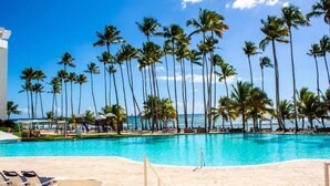 A poolside area with a clear view of the ocean, surrounded by tall palm trees.