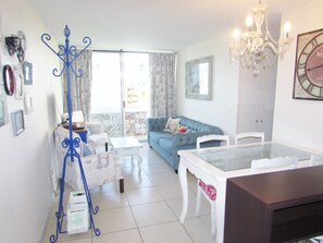 Ein Wohnzimmer mit einem blauen Sofa, einem weißen Esstisch und einer Kristallleuchter.