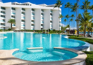 A large swimming pool with a hot tub, surrounded by a hotel building with multiple floors and balconies.