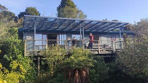 Una casa amb un balcó, envoltada de vegetació abundant.