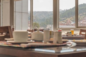 Un comedor con vistas a un paisaje montañoso a través de amplios ventanales.
