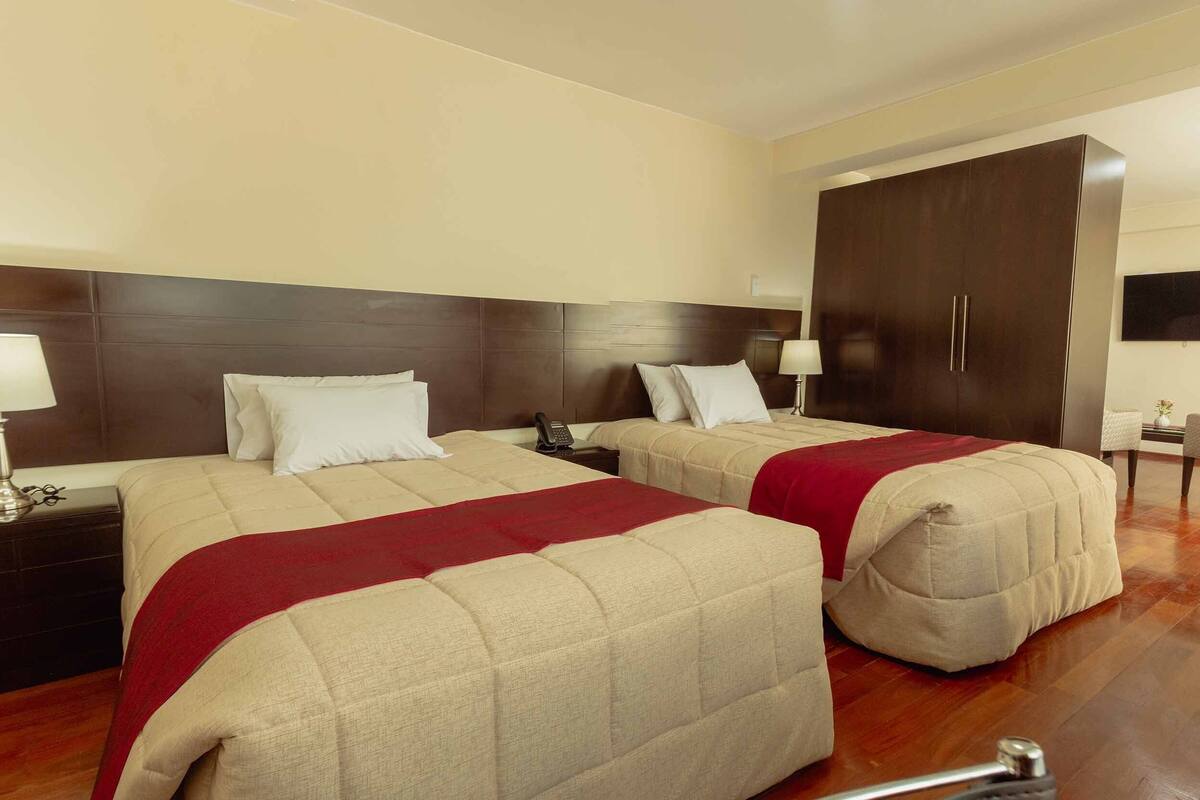 Une chambre d’hôtel avec deux lits, une armoire, un bureau et une chaise.