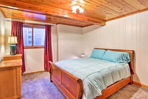 Un dormitorio con una cama de madera, una mesita de noche, una lámpara y una ventana con cortinas.