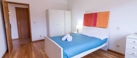 Un dormitorio con cama, armario, mesita de noche y cómoda.