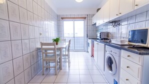 Une cuisine moderne avec des meubles blancs, un lave-linge et un coin repas comprenant une table et des chaises.