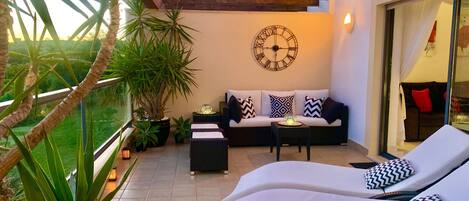 A modern outdoor lounge area with a sofa, two lounge chairs, a table, and potted plants.