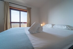 Una habitación de hotel con una cama, una ventana con cortinas y una luz nocturna.