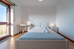 Relax in a serene space with a large bed, desk, and sliding door to an outdoor area.