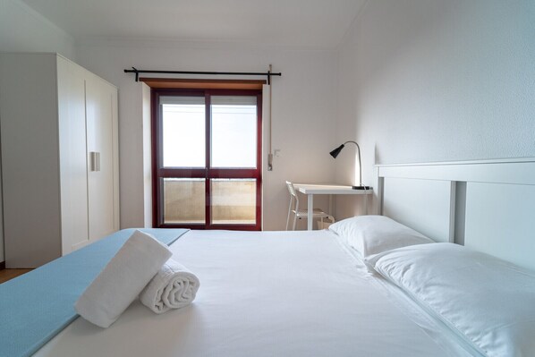 Relax in a serene space with a large bed, desk, and sliding glass door leading to a balcony.