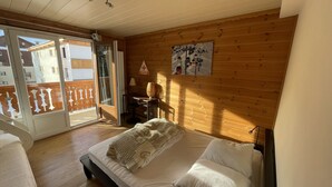 Une chambre à coucher avec un lit, un mur en bois, un tableau et une porte-fenêtre coulissante donnant sur l’extérieur.