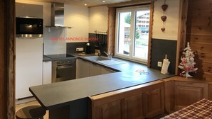 Une cuisine moderne dotée d’un four, d’un micro-ondes et d’une cuisinière encastrés, d’une grande fenêtre offrant une belle vue et de meubles de rangement en bois.