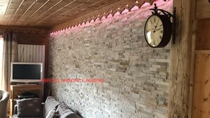 Un salon chaleureux avec un mur en briques, un plafond en bois et une horloge.