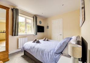 Cozy retreat with a large bed, wardrobe, and wall-mounted TV.