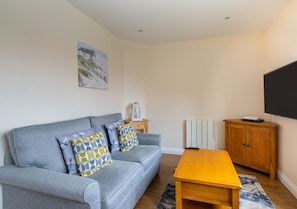 Relax in this stylish living room with a sofa, coffee table, and flat-screen TV.