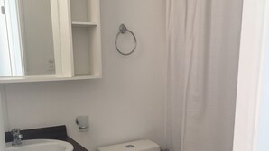 Une salle de bain avec des toilettes, un lavabo et un miroir au-dessus du lavabo.