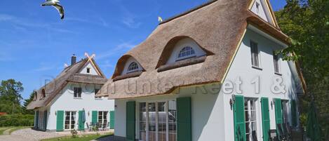 A traditional building with a thatched roof, green shutters, and a clear sky.