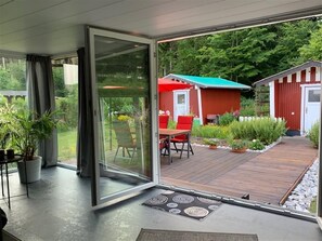 Una casa moderna con una puerta de cristal que da a una terraza de madera.