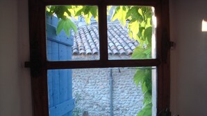 Una ventana con vista a un muro de piedra y un tejado de tejas.
