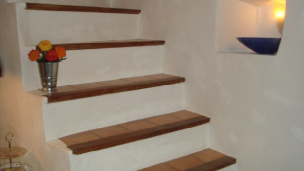 Una escalera de madera con un jarrón de flores en el primer escalón.