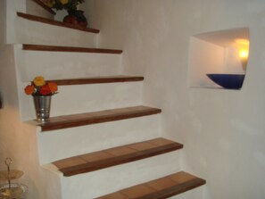 Una escalera de madera con un jarrón de flores en el primer escalón.