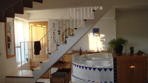 Amplia sala de estar con una escalera que lleva a un segundo piso, una bañera grande y un armario de madera.