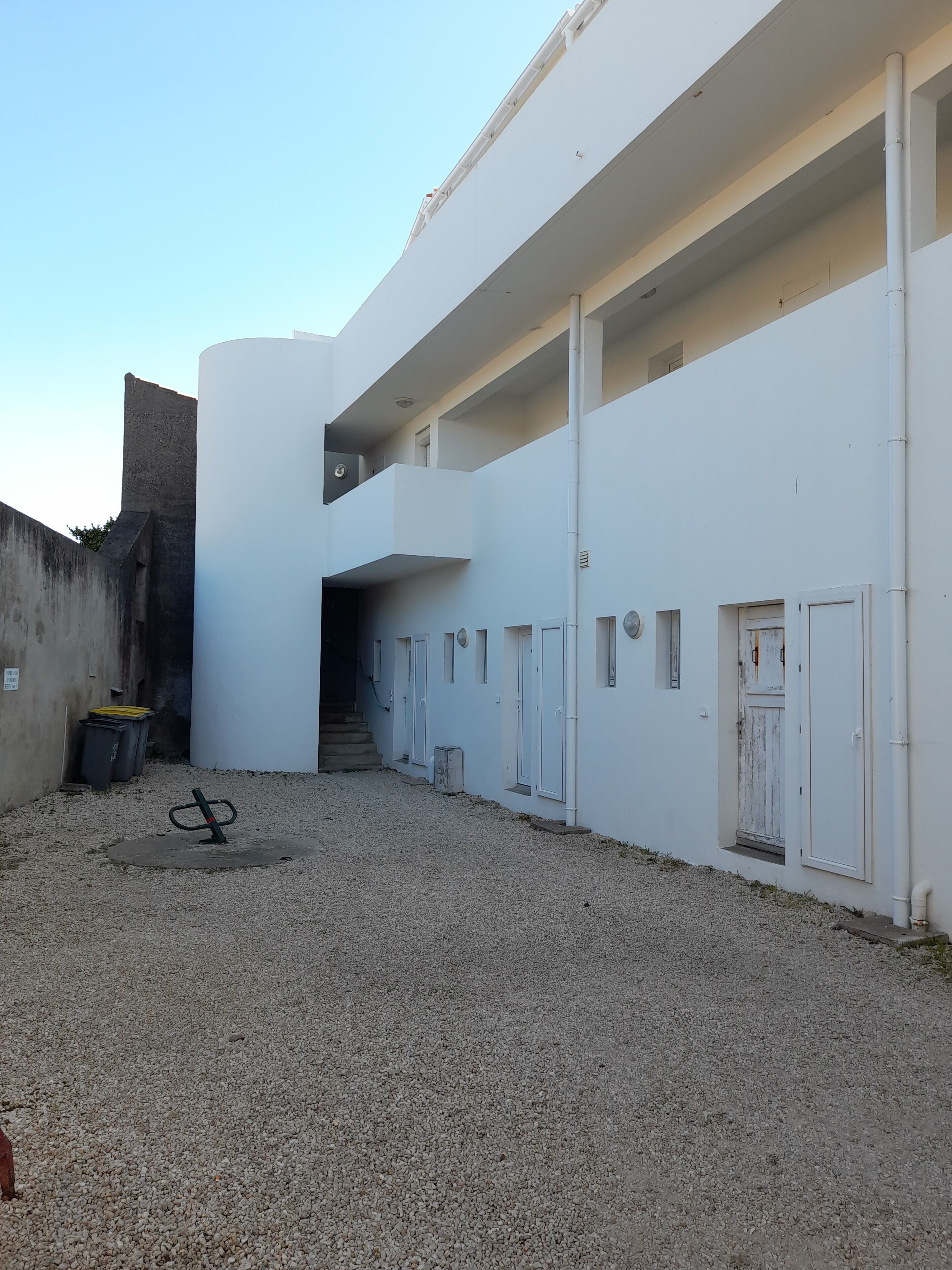 Un edificio moderno con fachada plana, una escalera central y varios ventanales pequeños.