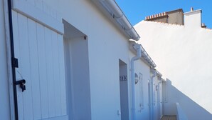 Un pasillo estrecho con paredes blancas y suelo de baldosas, que conduce a una puerta con el número 13.