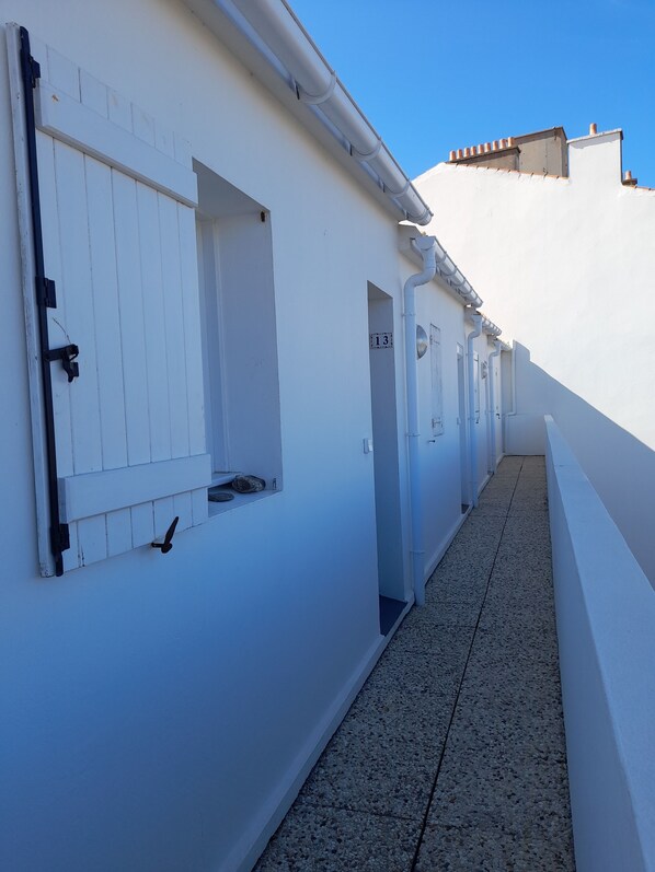 A narrow corridor with white walls and a tiled floor, leading to a door marked with the number 13. - APARTEMENT ILE DE NOIRMOUTIER 'Port de l'Herbaudière' 2 pers (Noirmoutier-En-L'île)