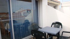 Un patio con una mesa, sillas, un portón corredero de vidrio y una pared blanca.