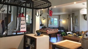 A cozy living room with a foosball table, a kitchen area with a hanging rack, and a dining table set for two. - Villa 6 People Saint Raphaël 5 min drive from the Beach, 2 min Golf courses (Saint-Raphaël)