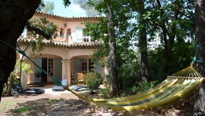 A hammock in a garden area with a building in the background. - Villa 6 People Saint Raphaël 5 min drive from the Beach, 2 min Golf courses (Saint-Raphaël)