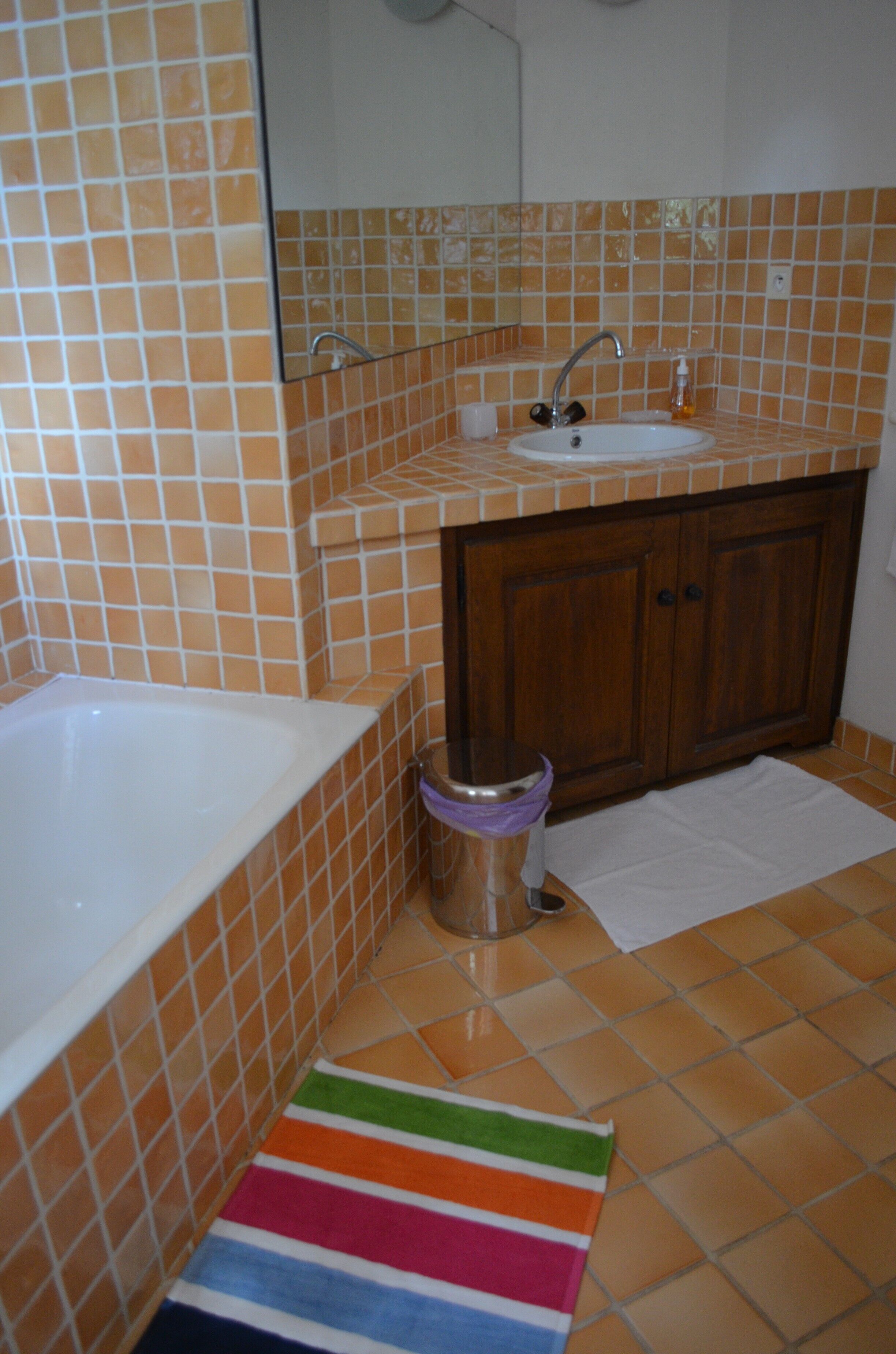 Ein Badezimmer mit einer weißen Badewanne, einem Waschbecken mit Wasserhahn und einem Holzkabinet.