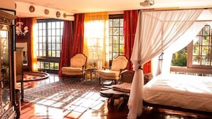 A traditional room with a large bed, two armchairs, a small table, and a large window with curtains. - Villa Felicche Búzios (Búzios)