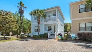 A two-story building with a balcony, a covered porch, and a driveway. - Blue Mountain Beach, Sleeps 12, Steps from Pool + Free Attraction Tickets! (Santa Rosa Beach)