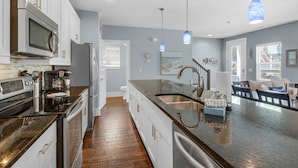 A modern kitchen with stainless steel appliances, a wooden floor, and a large island with a sink. - Blue Mountain Beach, Sleeps 12, Steps from Pool + Free Attraction Tickets! (Santa Rosa Beach)