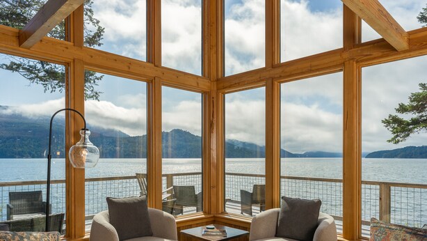 Cómoda zona de estar con dos sillones y una mesita, con vistas a un lago y montañas al fondo.
