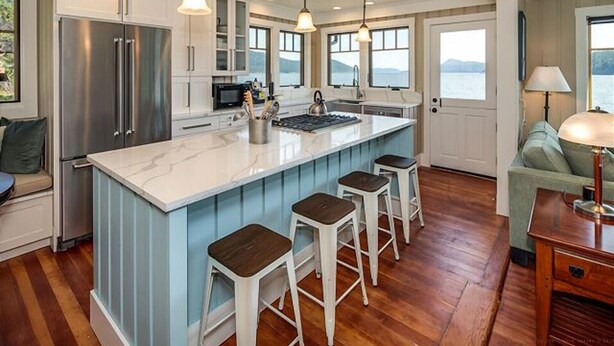 A kitchen with a large island, bar stools, stainless steel appliances, and a view of the outdoors. - Orcas Island, Juniper House #212 (Eastsound)