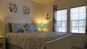 Ein Schlafzimmer mit einem Bett, Nachttischen, einer Lampe und Kunstwerken an den Wänden.